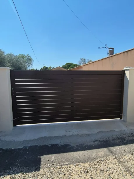 Portail coulissant lames persiennées RAL 8014 aluminium La Toulousaine Laudun-l'Ardoise vue extérieure