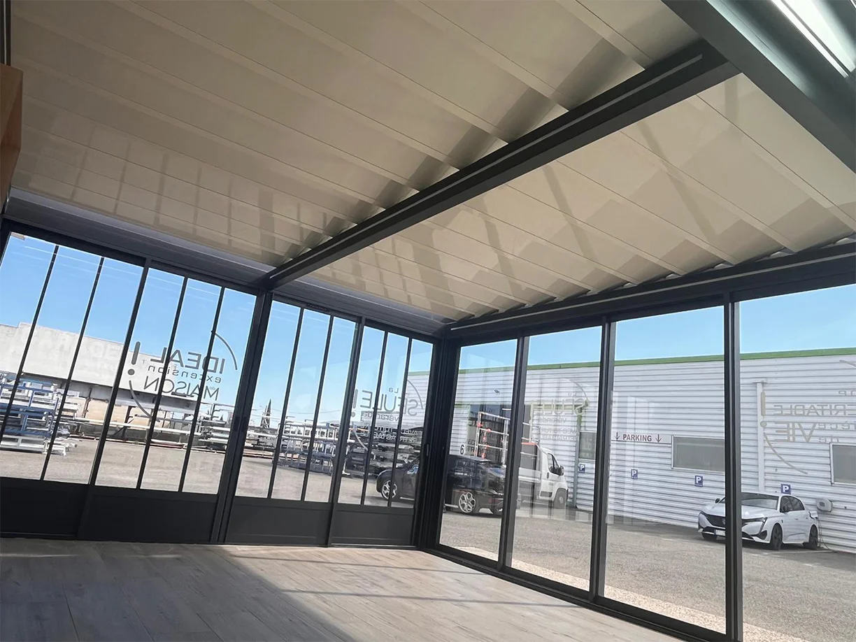 Véranda extension aluminium toit rétractable Ciel Ouv’air Carré 2 Rêve showroom TRIOLA vue intérieure toit semi fermé