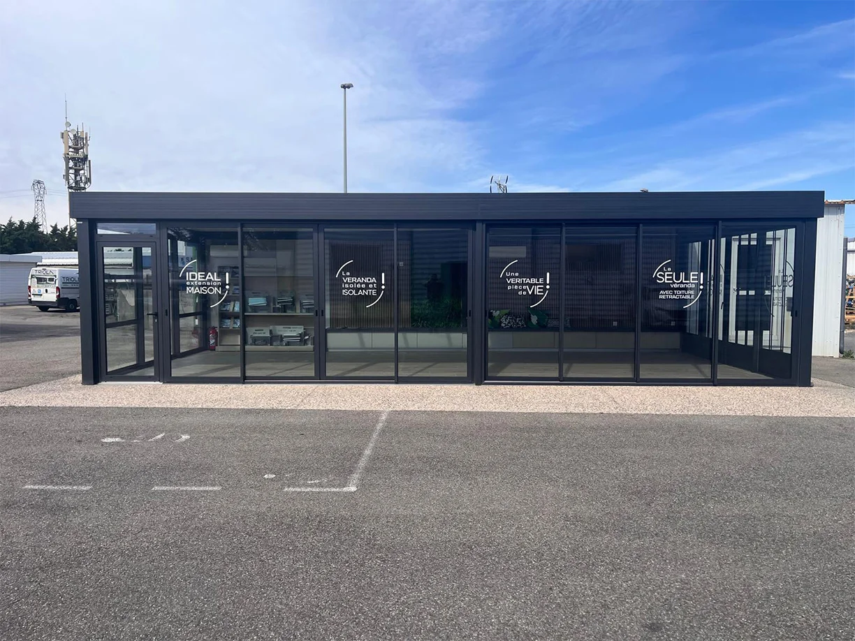 Véranda extension aluminium toit rétractable Ciel Ouv’air Carré 2 Rêve showroom TRIOLA vue extérieure face